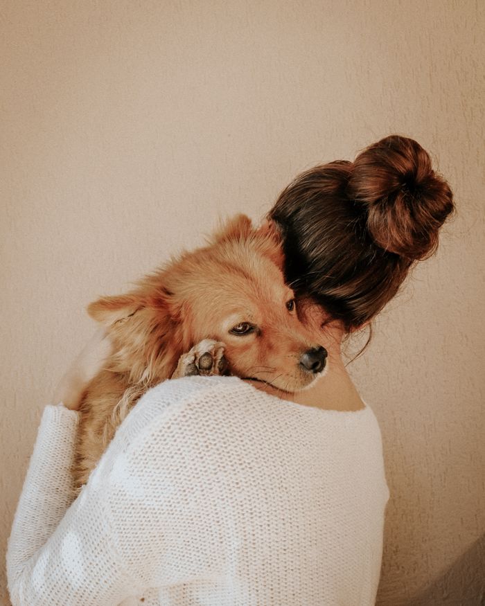A woman affectionately hugs her golden retriever, highlighting the bond between pet and owner.